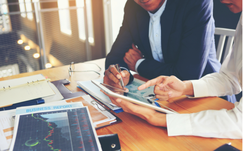 Two-business-men-at-a-table-looking-over-graphs-together